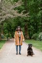 Woman in Brown Coat Holding Black and Brown Short Coat Dog