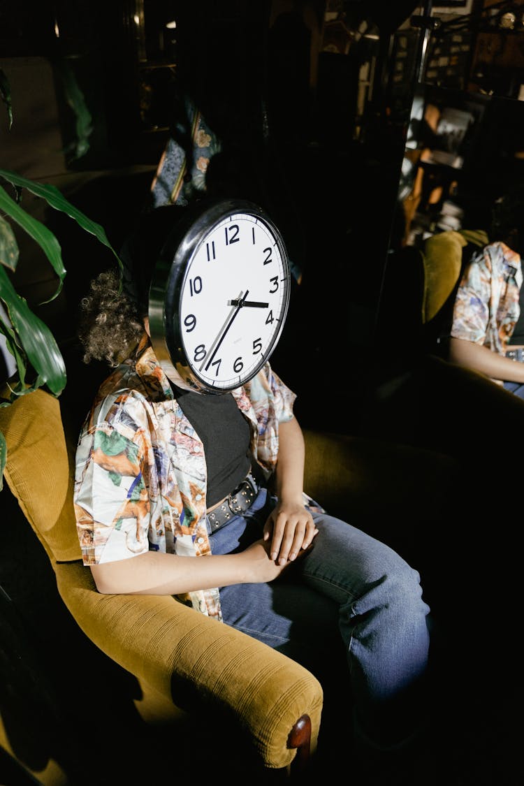 A Silver Round Clock Covering The Person's Face 