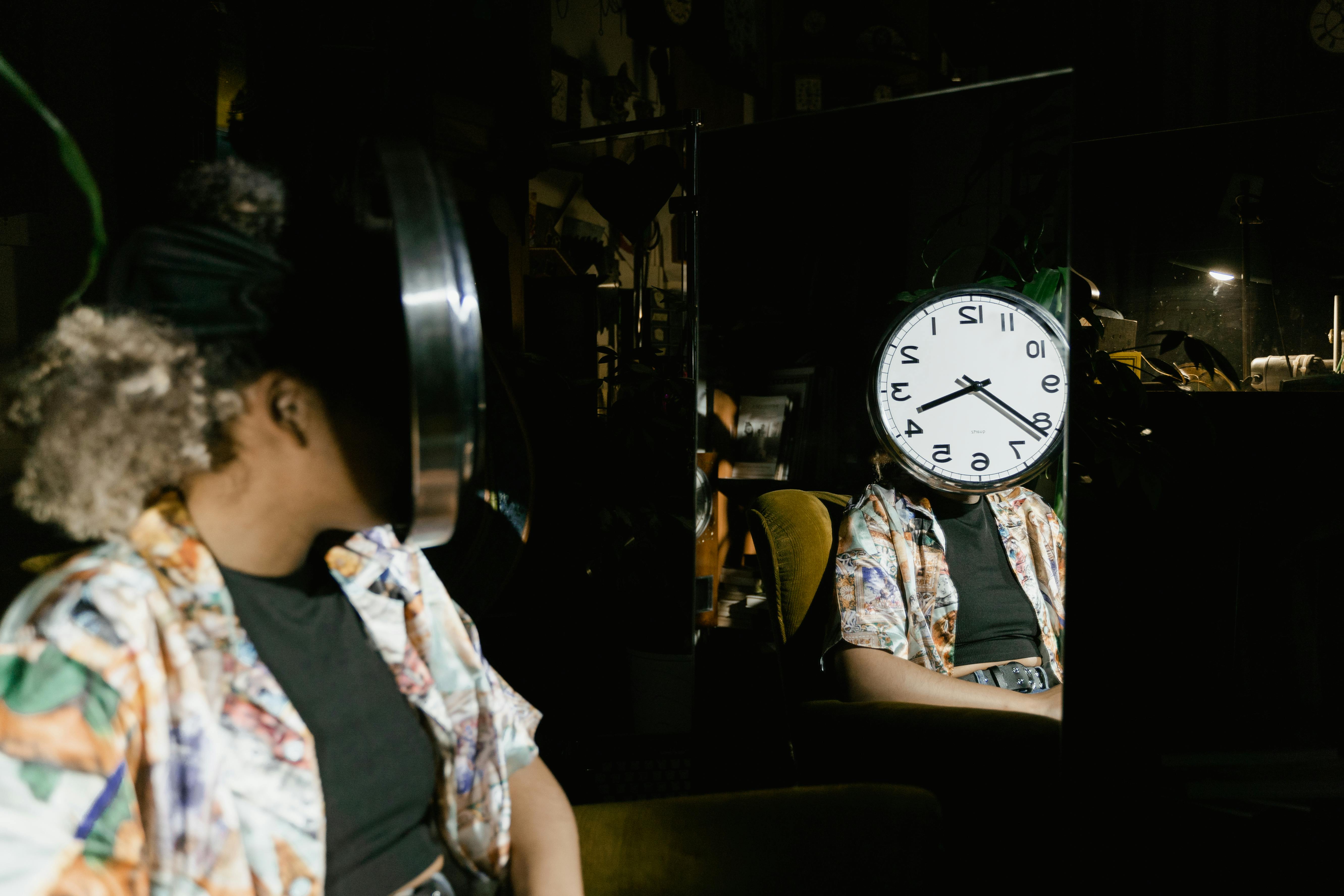 https://www.pexels.com/photo/woman-sitting-in-front-of-a-mirror-with-a-clock-dial-covering-her-face-8327643/