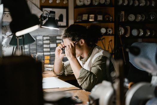 Expert watchmaker focusing on delicate repairs in a well-lit workshop with magnifying loupe.