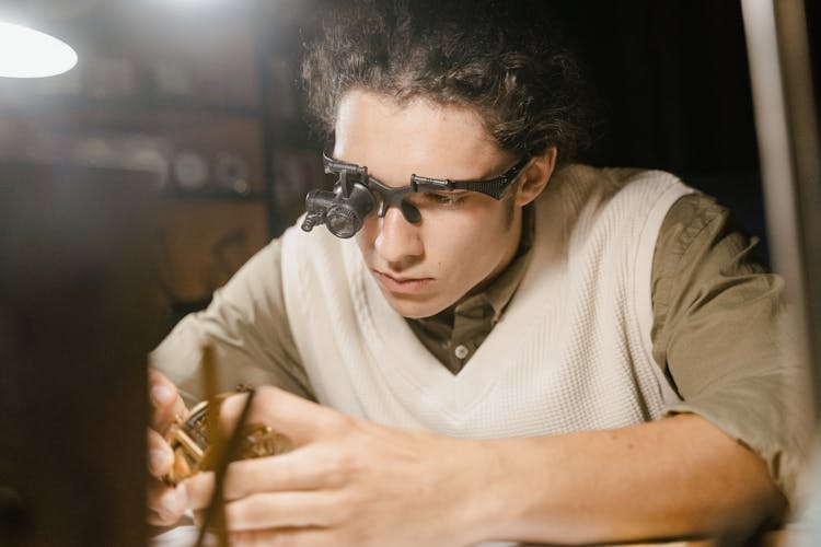 Man Wearing A Magnifier Holding A Gold Watch