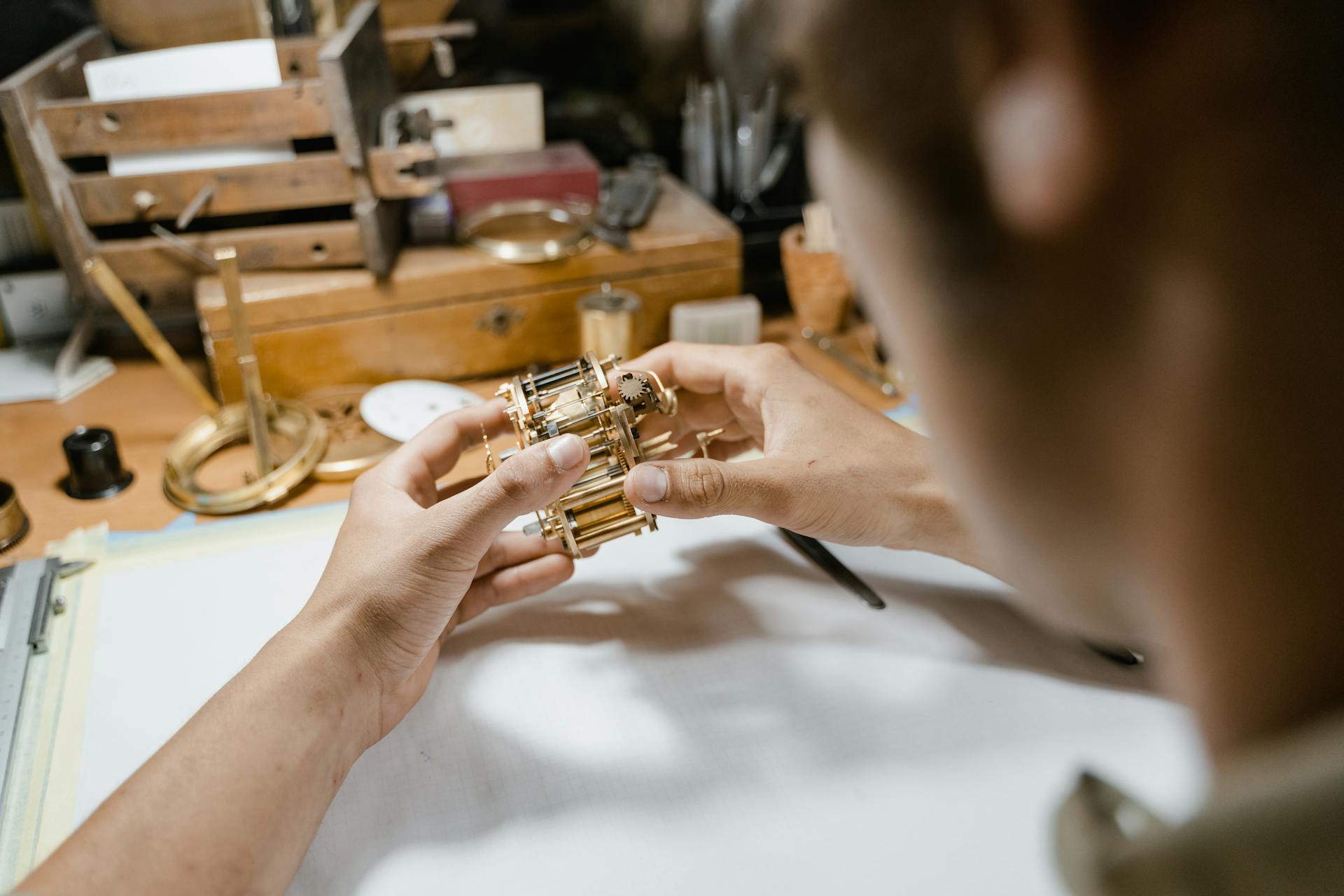 Skilled watchmaker repairing an intricate clock mechanism with precision tools on a cluttered workbench.