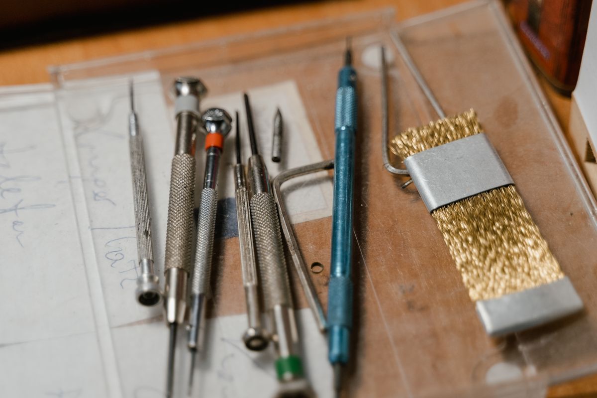 Precision hand tools and a brass brush laid out on the fettling bench