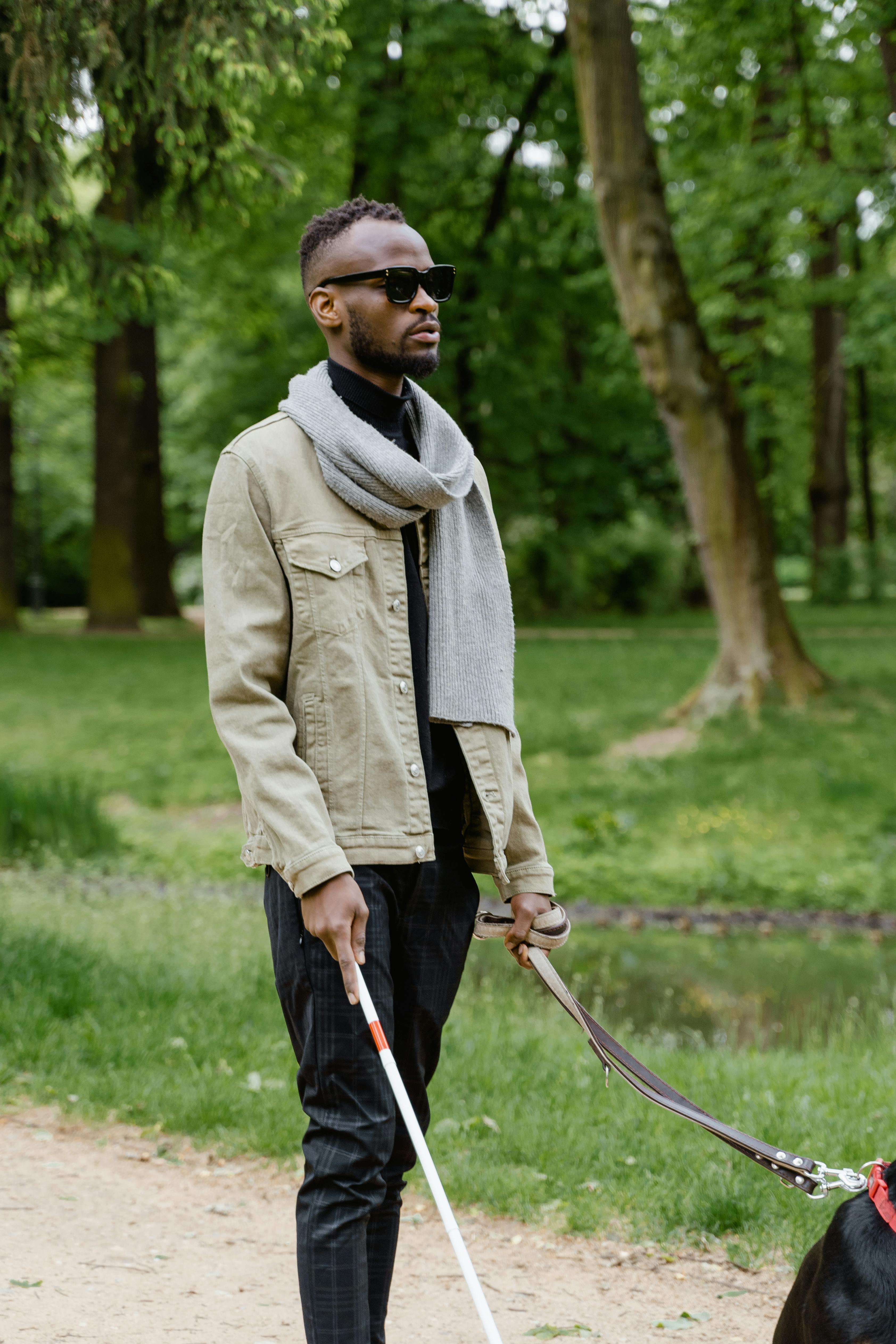 man in gray coat holding walking stick while walking