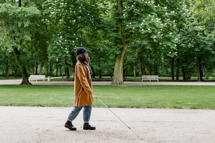 A Woman In Brown Coat Walking On Pathway