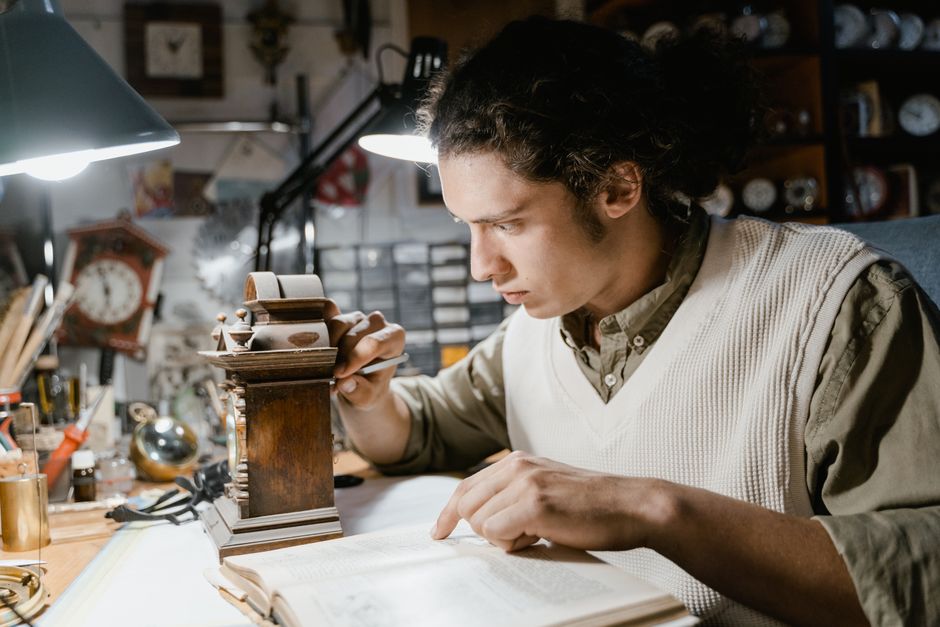 Focused young watchmaker meticulously working on a clock repair in a cluttered workshop.