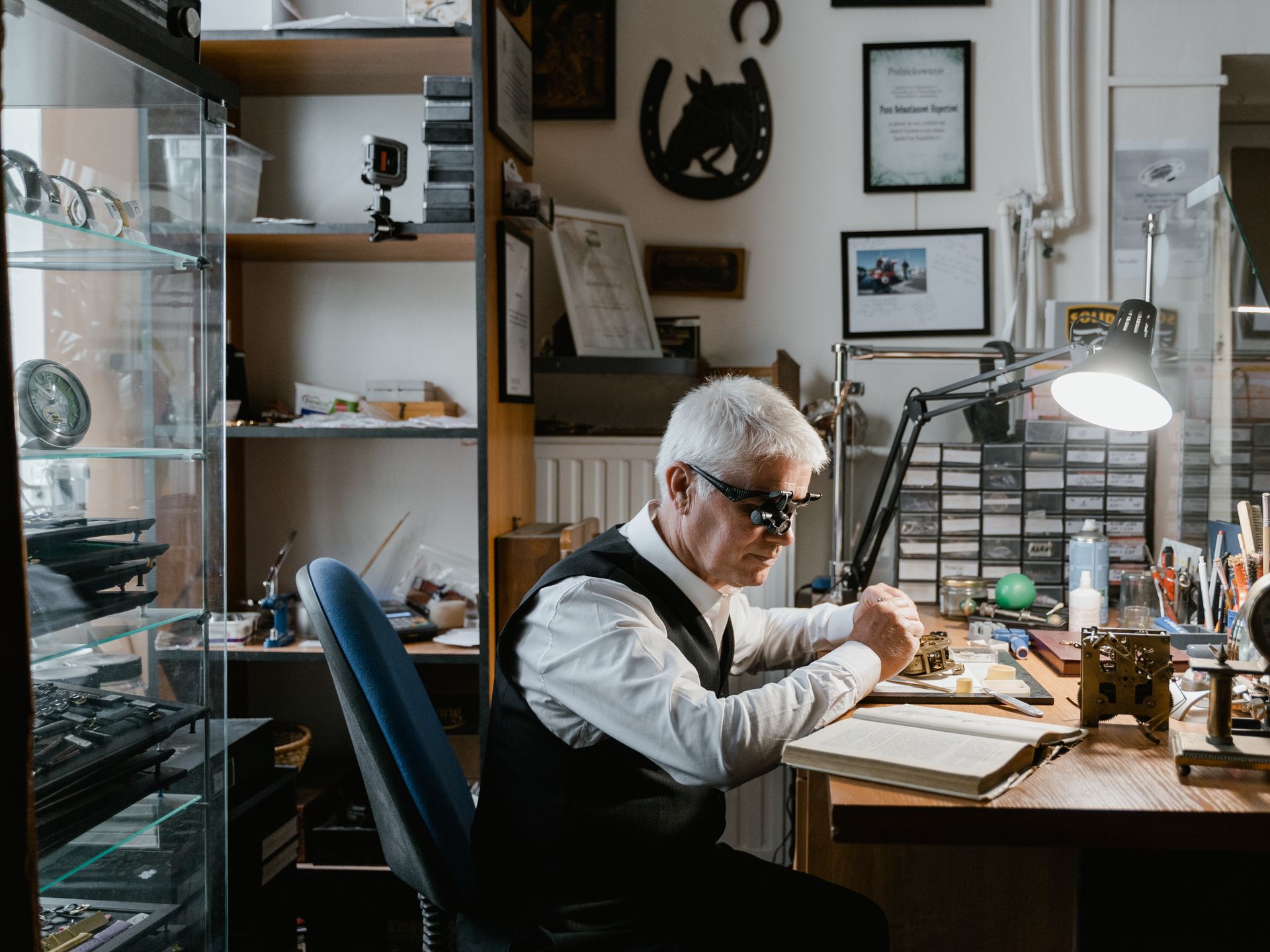 Expert craftsman meticulously repairing a watch in a vintage-style workshop filled with tools.