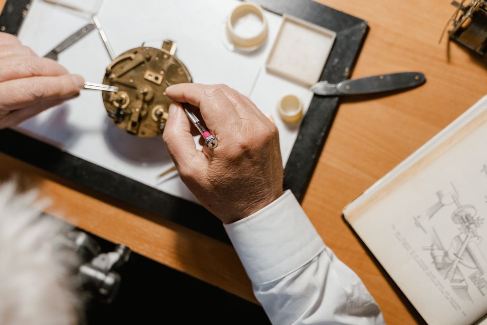 A watchmaker at the bench adjusting a movement, photo by Tima Miroshnichenko on Pexels