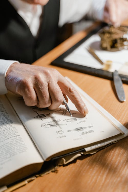 Elderly Man Pointing at Illustration in Book