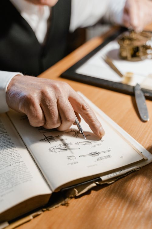 Free Senior man pointing at a technical illustration in a book during study or research. Stock Photo