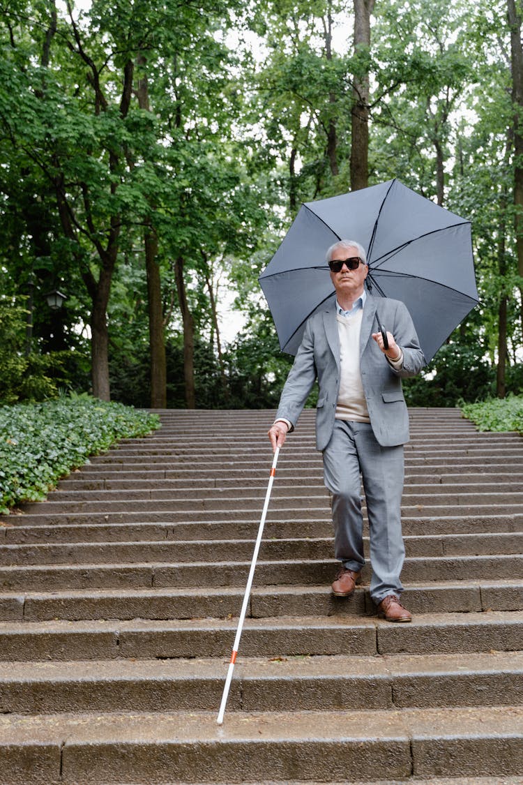 A Blind Man In Gray Suit With Umbrella