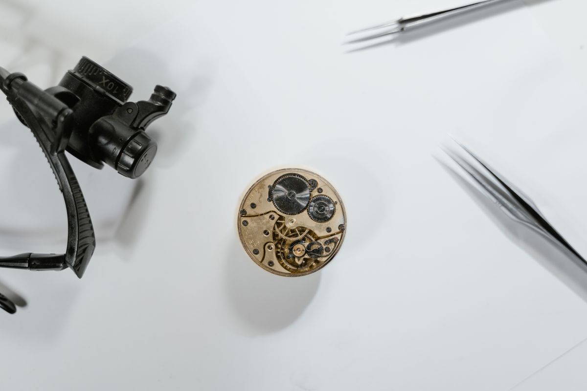 Vista superior de un mecanismo de reloj antiguo con herramientas sobre la mesa