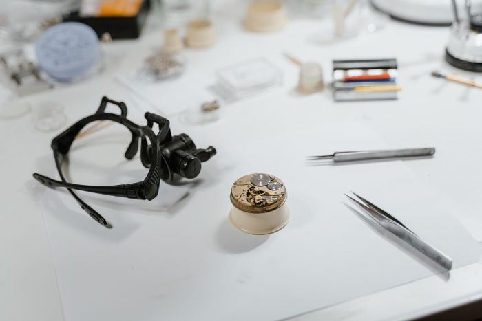 Tweezers, a loupe visor and a movement laid out on a watchmaker's bench, photo by Tima Miroshnichenko on Pexels