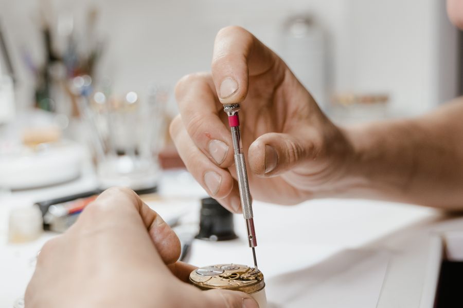 Hands working a movement with a screwdriver