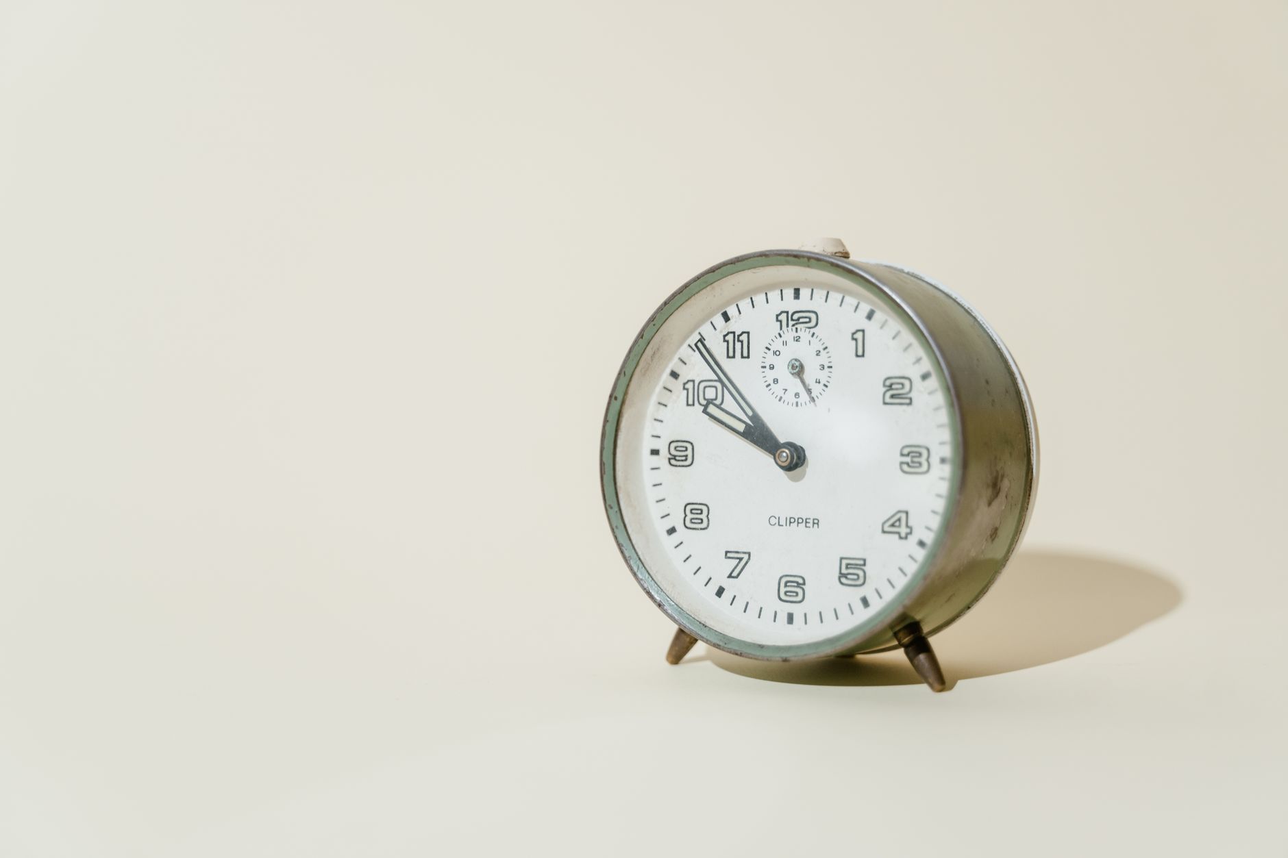 Close-up of a vintage metal analog clock on a light background, showing morning time.