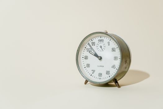 Close-up of a vintage metal analog clock on a light background, showing morning time.