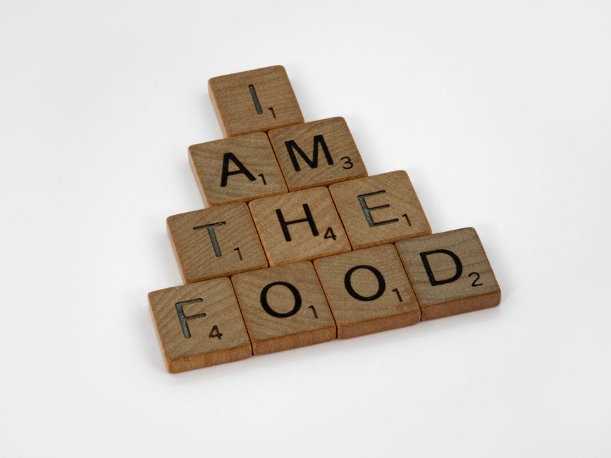 Wooden scrabble tiles spelling food-related words on white surface`