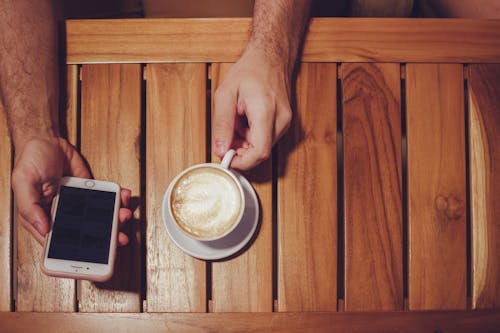 Person Holding Ausgeschaltet Gold Iphone 6 Mit Etui Und Weißer Keramikschale Mit Latte Gefüllt