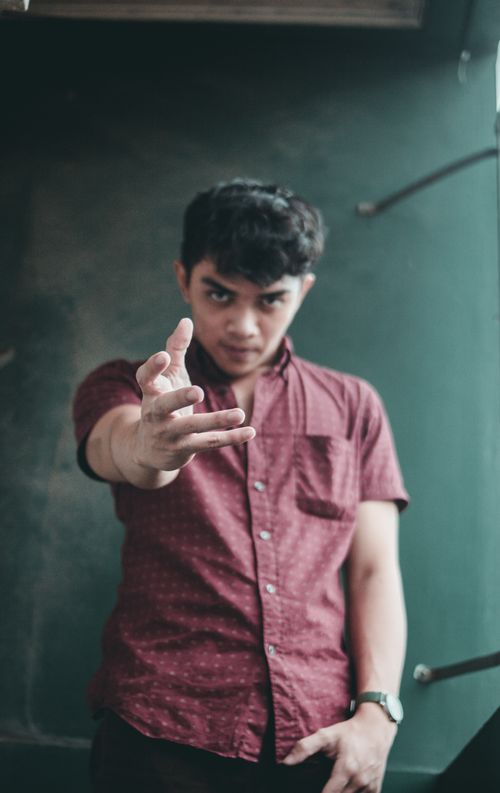 Free Portrait of a young man extending his hand with intense expression indoors. Stock Photo