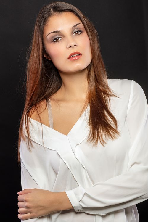 Free Stunning portrait of a woman posing against a dark background, highlighting her elegance and beauty. Stock Photo