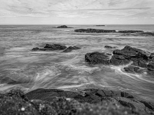 Free Captivating black and white photo of rocky seashore with waves crashing. Stock Photo