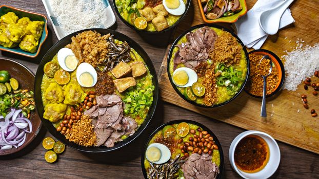 A vibrant and appetizing display of Asian rice porridge with various toppings like eggs, peanuts, tofu, and lime.