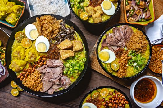 Colorful bowls of Filipino Arroz Caldo with various delicious toppings on a wooden table.