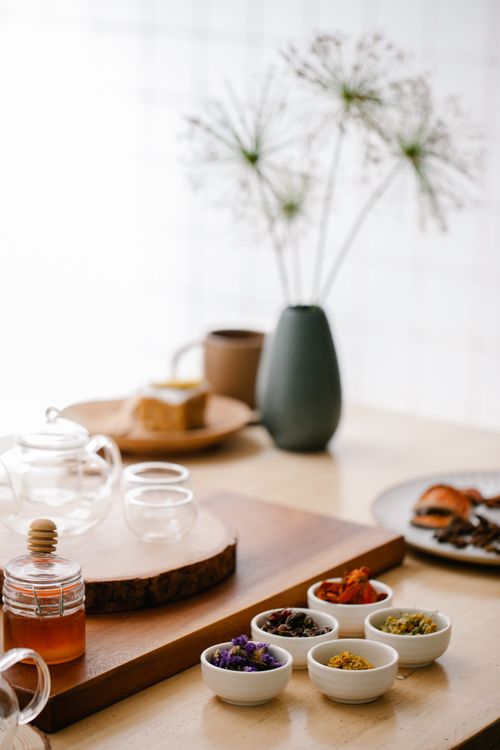 Free A cozy table setting with assorted herbs and a glass teapot, creating a warm ambiance. Stock Photo