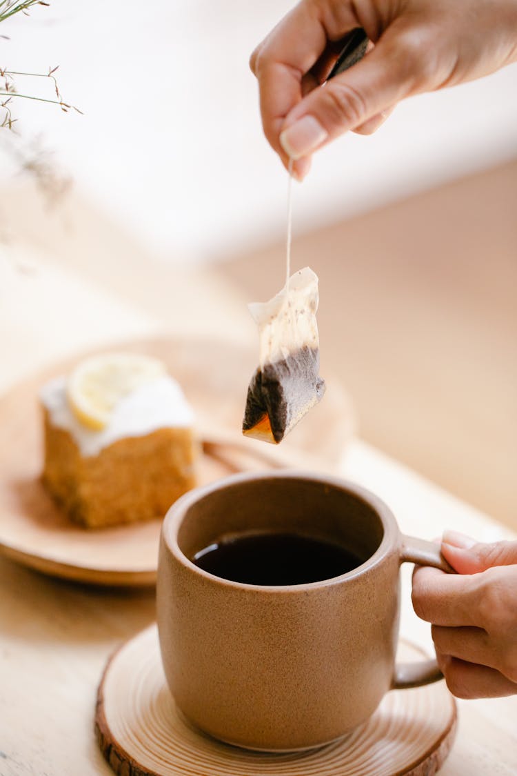 Woman Taking Out Teabag From A Beige Mug