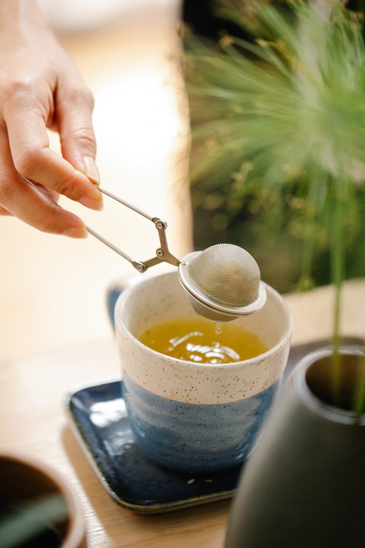 Close-up Of Person Making Tea With Infuser