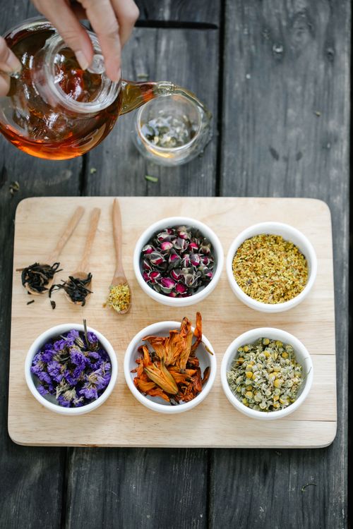 Free Top view of various herbal tea ingredients in bowls with a teapot, showcasing a natural and organic feel. Stock Photo