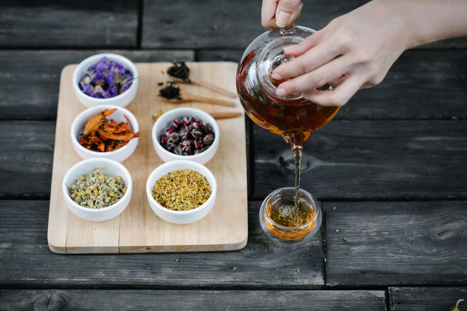Taza de infusión de hierbas rodeada de plantas frescas de menta y manzanilla sobre una mesa de madera