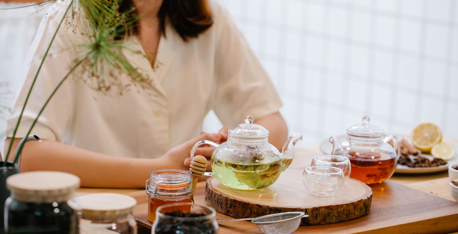 Tea being poured with honey and dried herbs on the table