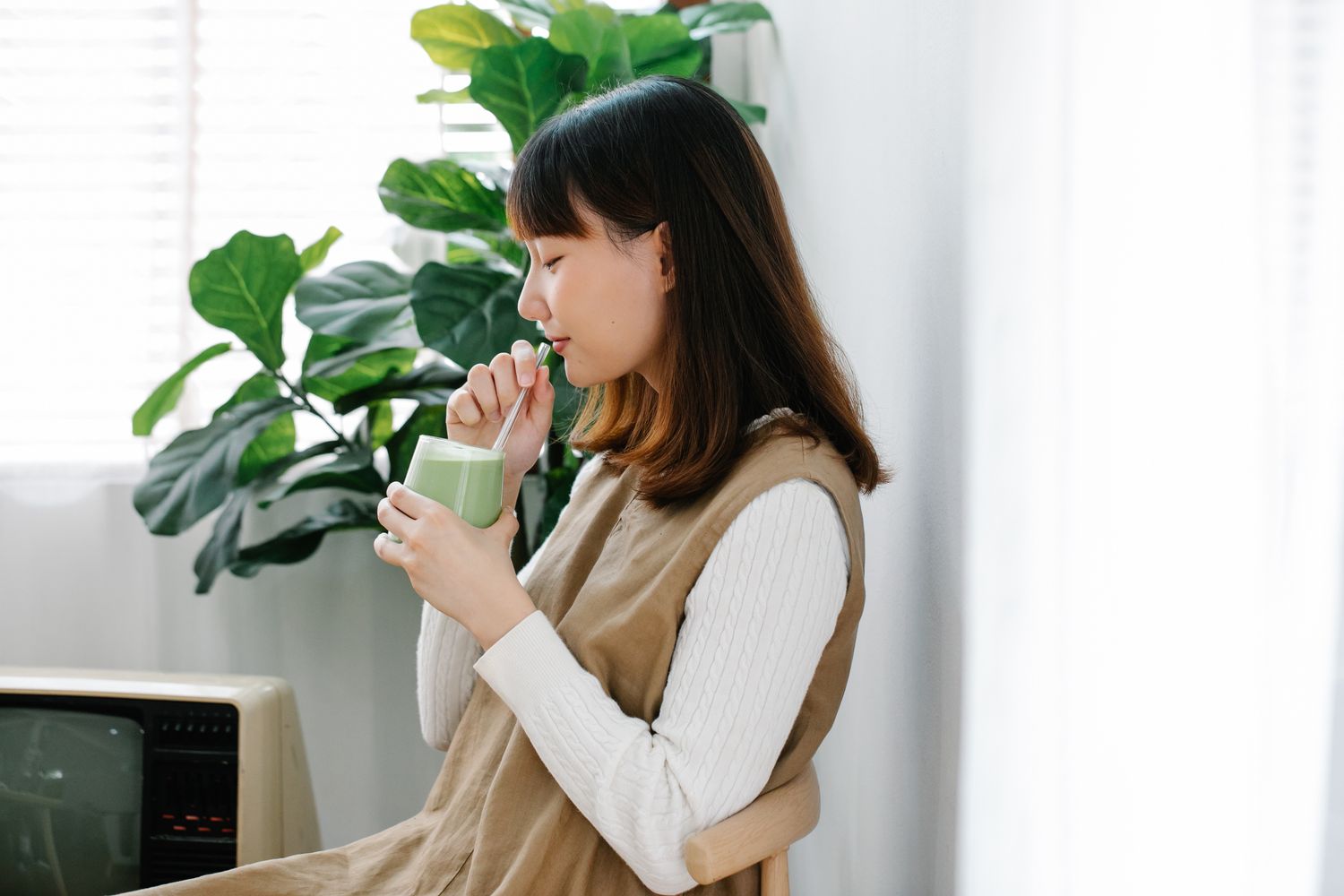 A calm moment with a fresh green drink beside a houseplant