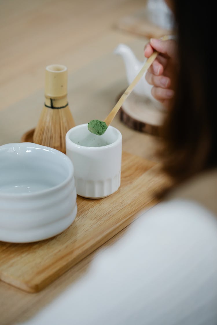 Person Getting Green Powder Using Wooden Spoon 