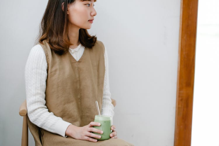 Woman Holding Green Juice On Clear Glass 