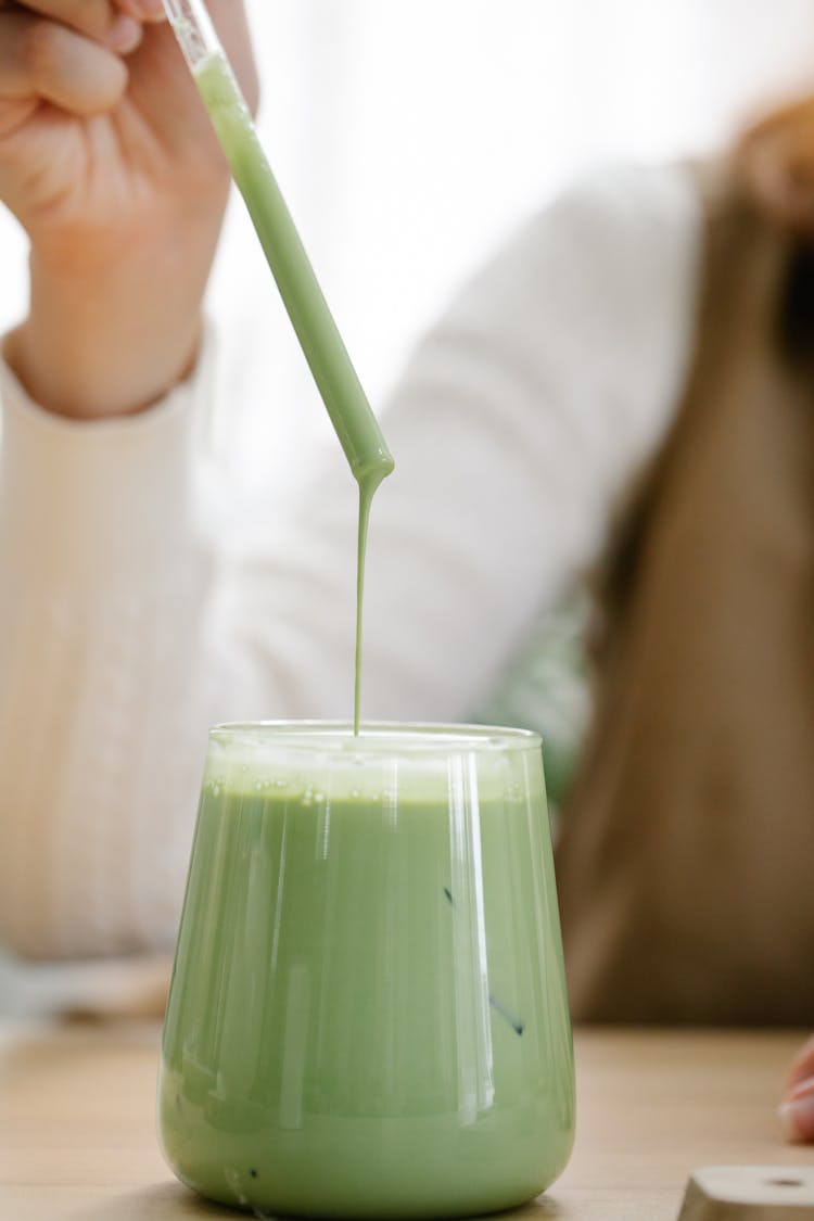 Woman Pulling Straw Out Of Glass Of Thick Milk Tea