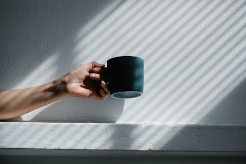 Free Hand Holding Mug Towards Sunlight Stock Photo