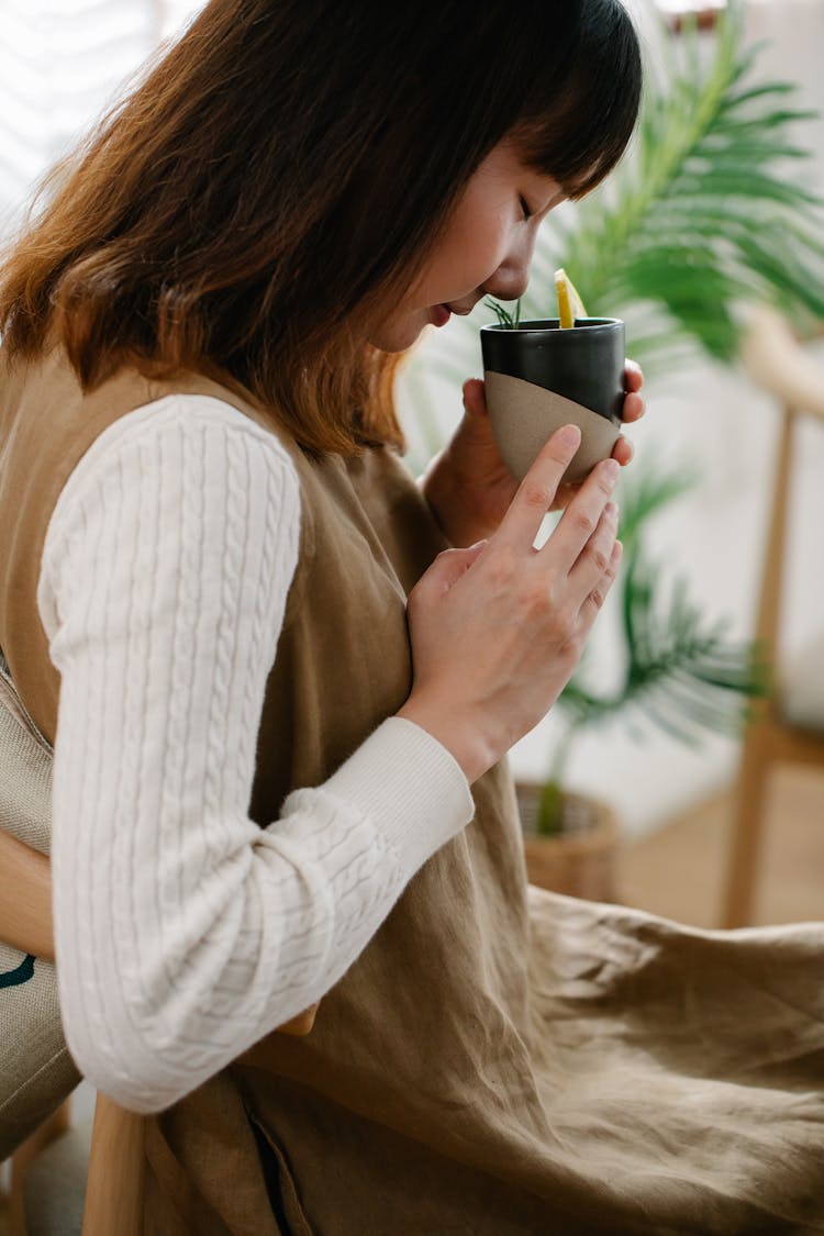 Woman Smelling Cup Of Tea With Lemon