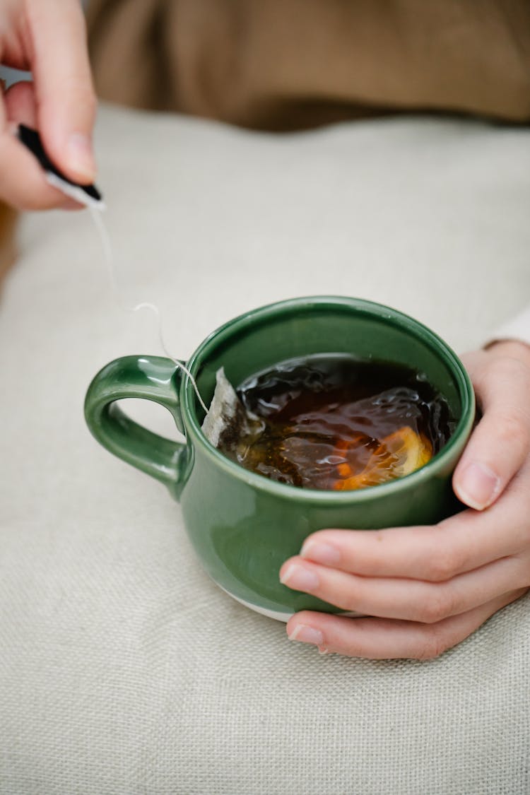 Hand Holding Mug Of Tea With Lemon Slice