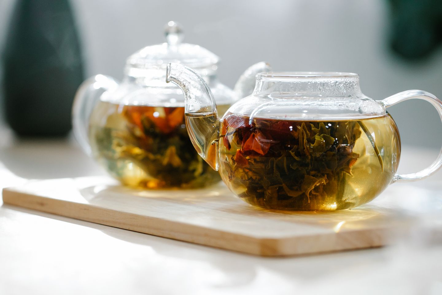 Two glass teapots of flowering tea on a wooden board, the afternoon ritual Whittard has been selling since 1886.