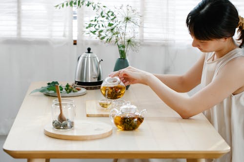 Woman Pouring Tea From a Glass Teapot 