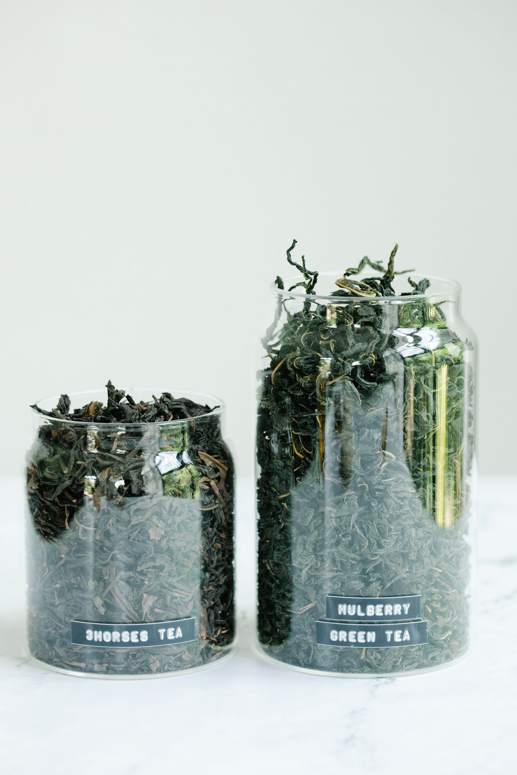 Glass jars of dried tea leaves in a clean kitchen setting