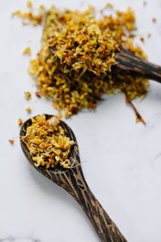 Detailed view of dried flowers elegantly arranged on wooden spoons on a white surface.