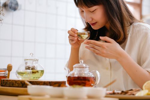 Free A woman savoring a cup of aromatic herbal tea in a cozy indoor kitchen setting. Stock Photo