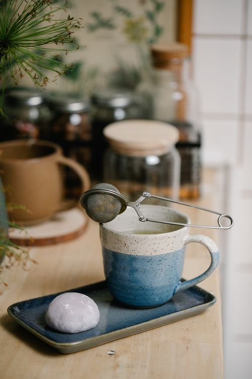 Free A serene tea setup featuring a ceramic mug, infuser, and mochi, perfect for a calming break. Stock Photo