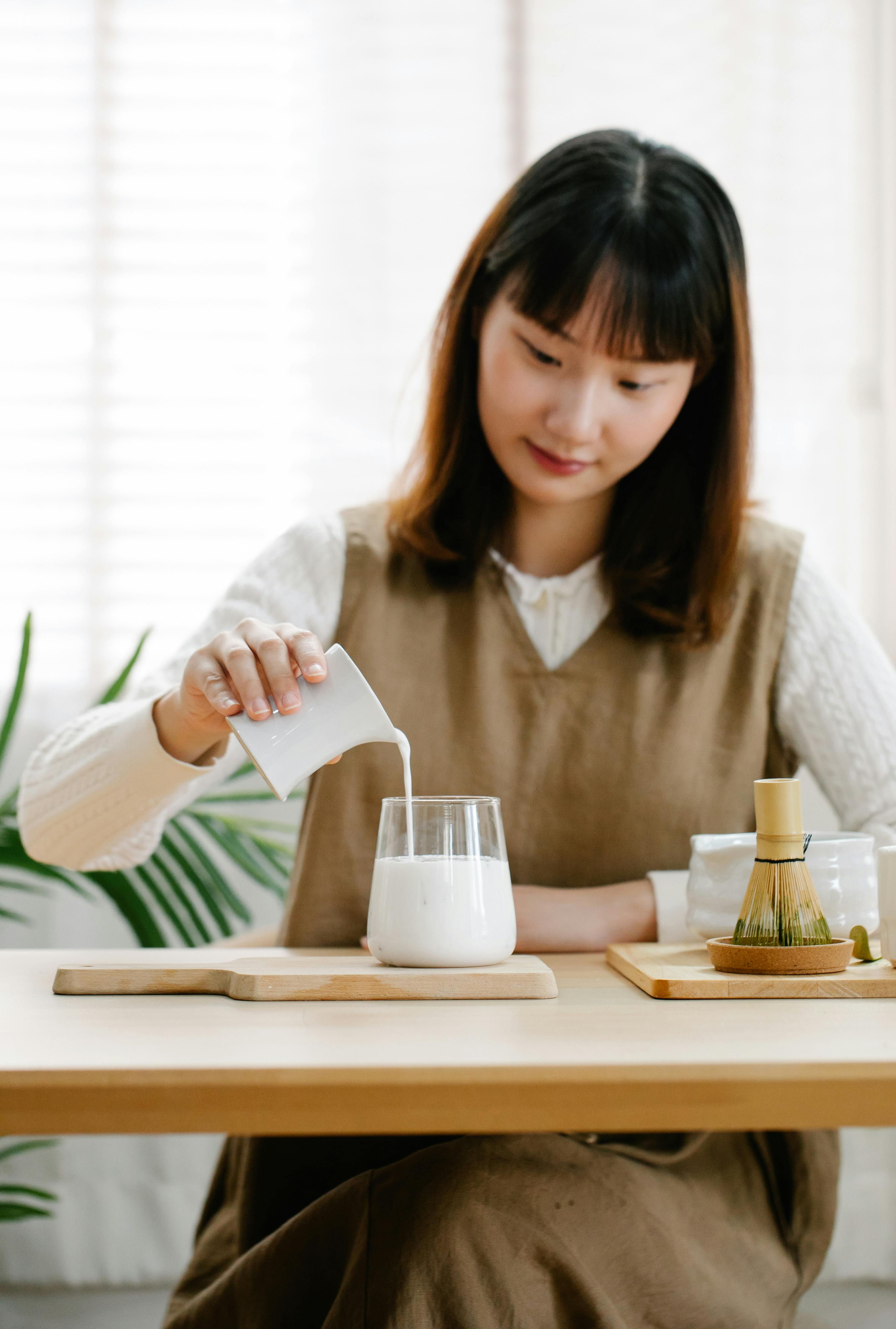 woman in white long sleeve shirt pouring milk