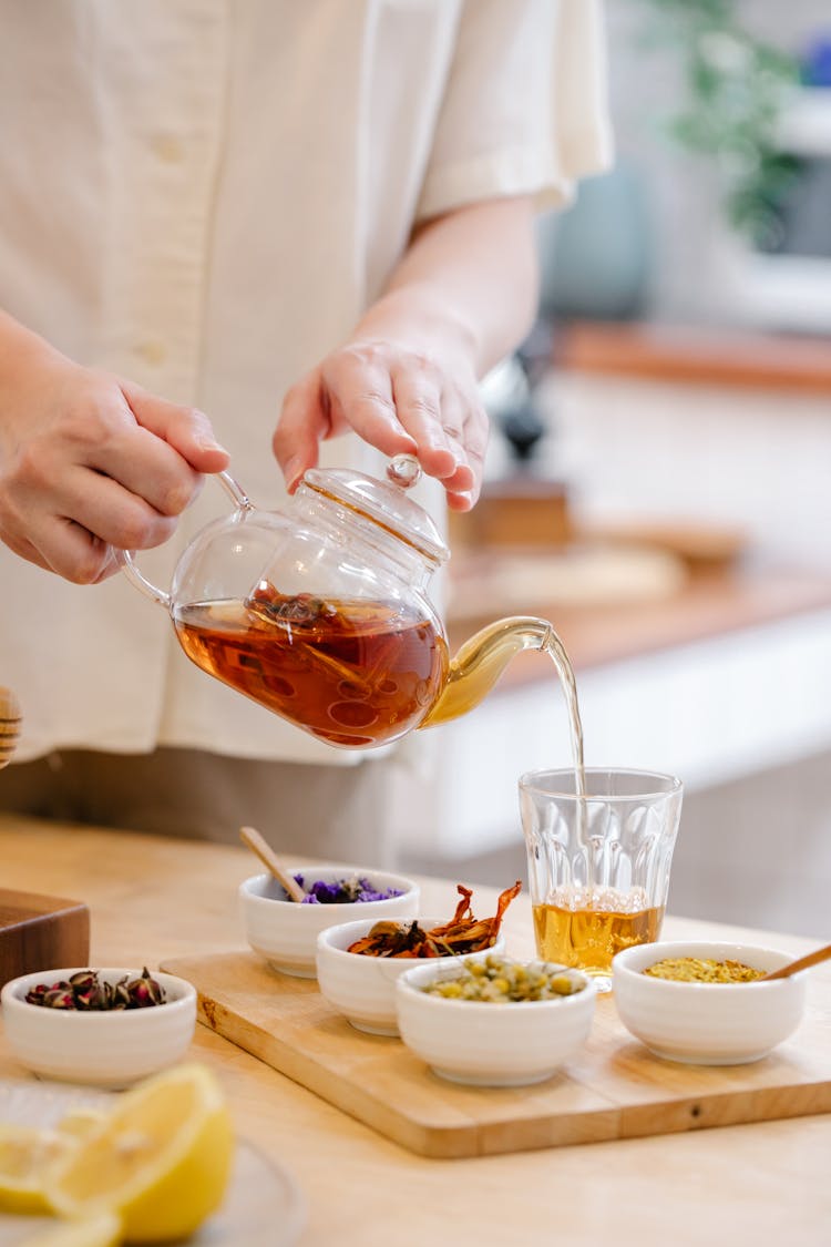 Person Pouring Beverage On Clear Glass 