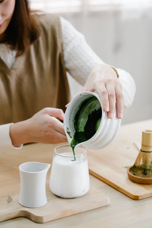 Woman Pouring Matcha into a Cup with Milk 