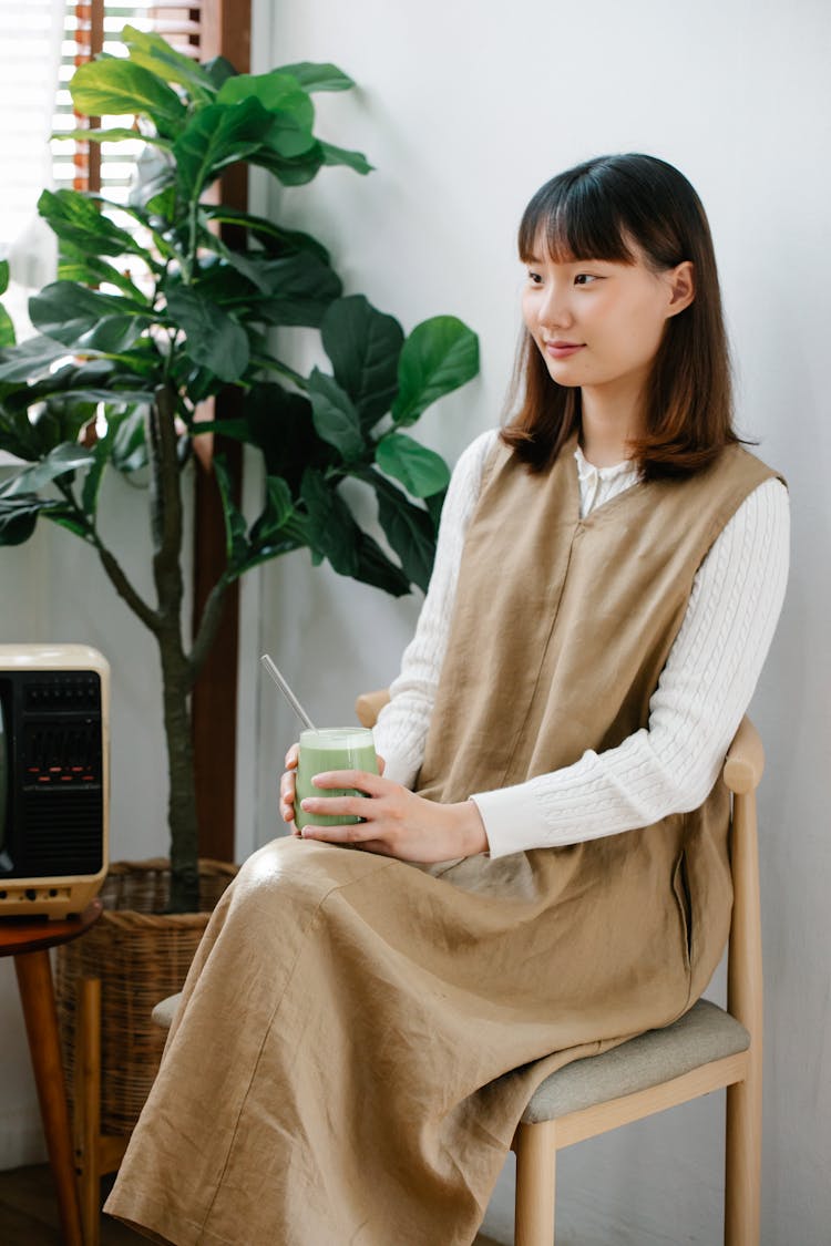 Woman Sitting In Chair Drinking Matcha